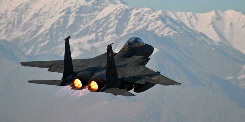 Fighter jet flying over snowy mountains