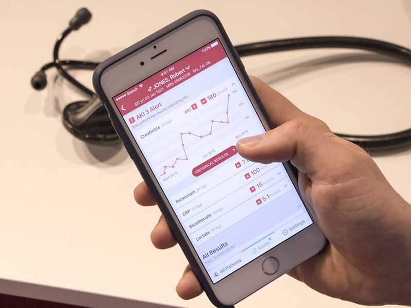 Hand holding a smartphone with the app featuring medical records for a patient named Robert Jones
