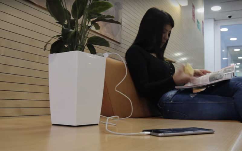 Girl reading a magazine, while a plant pot is charging her smartphone