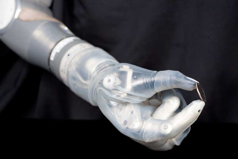 A robotic prosthetic hand holding a coin