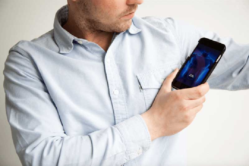 A man in a shirt pointing his smartphone at his armpit