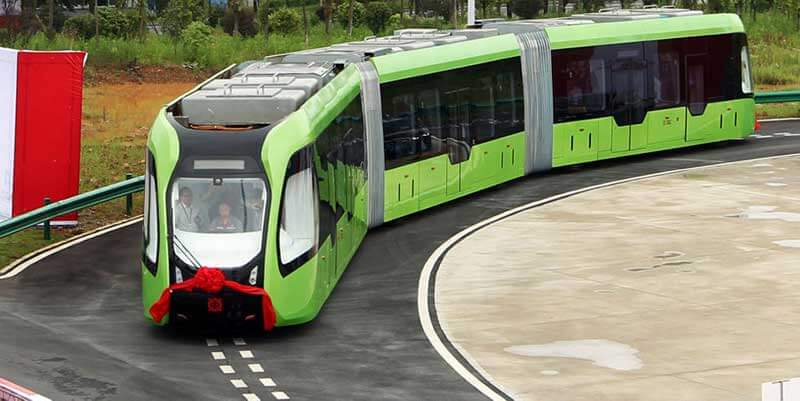 autonomous green train with a red bow at its front cruising the road
