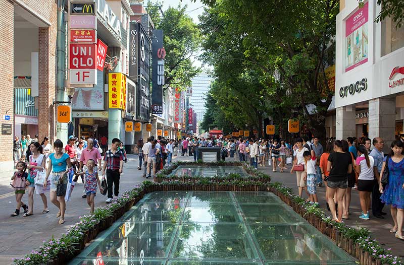  A shopping street in China with people walking in the sunshine