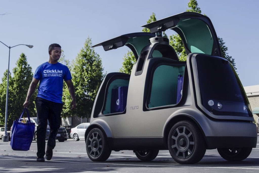 A man with a grocery bag approaching a Nuro self-driving grocery delivery vehicle