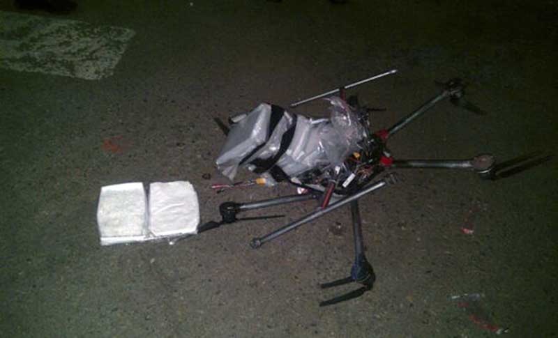 Crashed black drone equipped with several packages wrapped in plastic