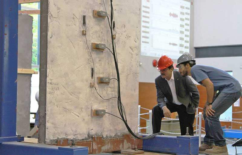  Two people with hardhats looking at a concrete wall 