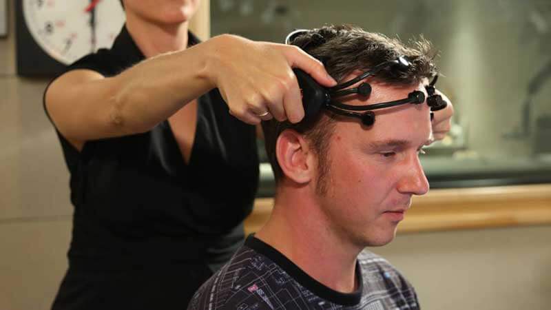 A woman puts the Emotiv headset on a man's head