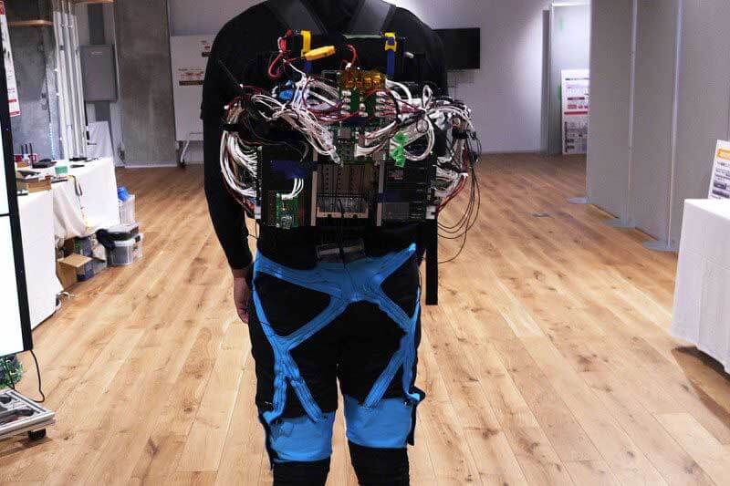 Back view on man standing straight and wearing a robotic exoskeleton