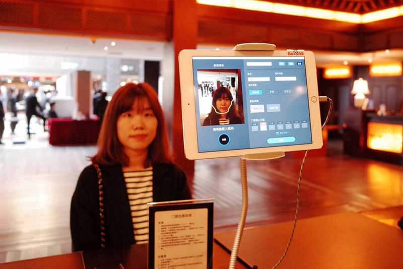A woman standing in front of a facial recognition device that’s mapping her face