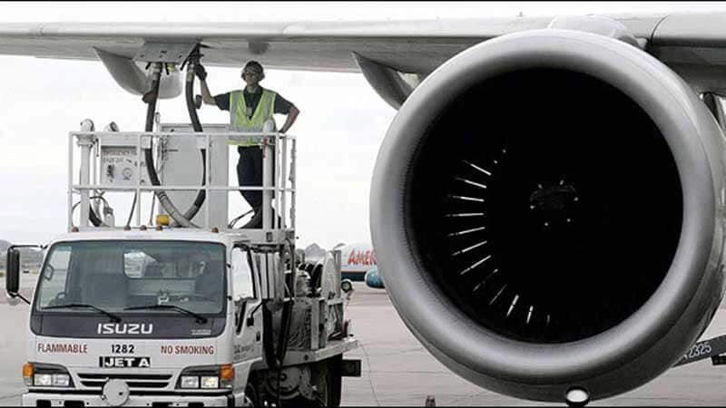 Man refuelling airplane next to airplane engine