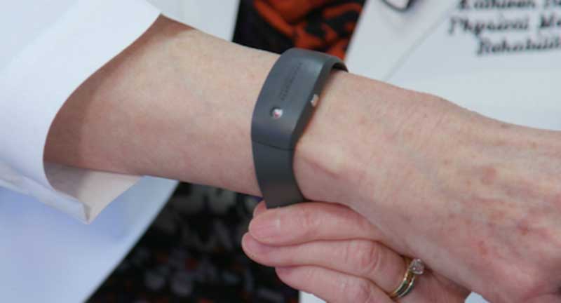 Black smart bracelet worn on a woman’s wrist