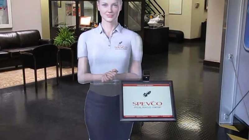 A hologram of a woman standing in a lobby with a screen next to it