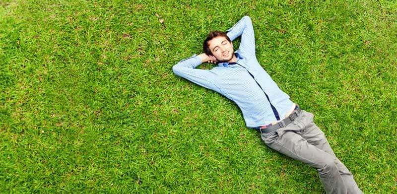 Young man lying in bright green grass