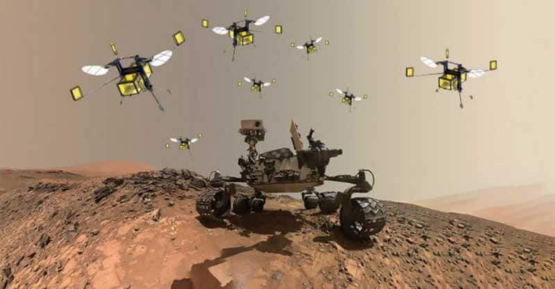 A rover driving over sand dunes surrounded by bee-like flying robots