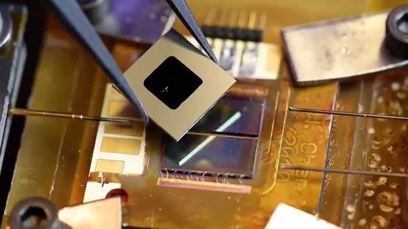 Close-up of a tiny solar cell being placed with tweezers
