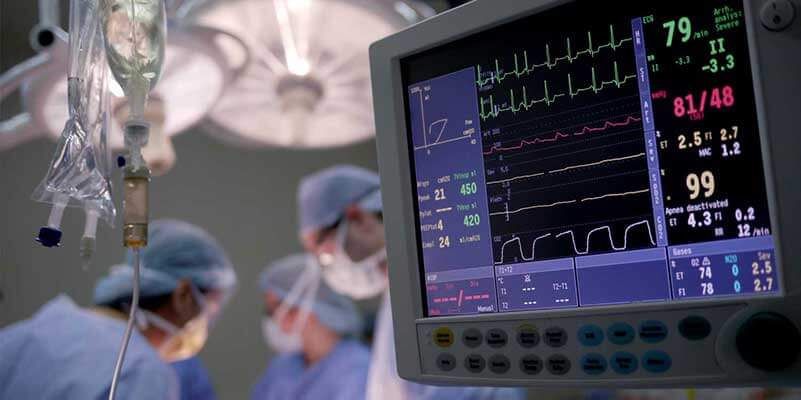 Surgeons in operating room with vital stats monitor