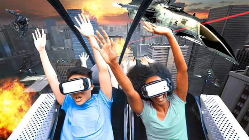 Two people wearing VR headsets and enjoying a ride on a virtual roller coaster