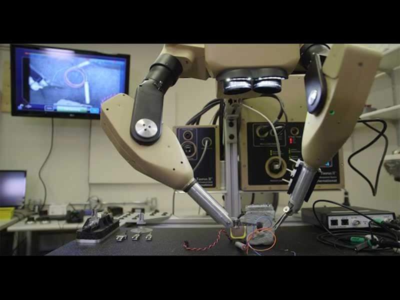 A surgical robot interacting with an object in a lab with its two robotic arms