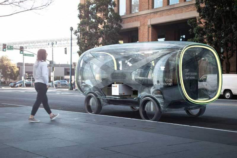 A woman approaches the self-driving Cody vehicle on the street