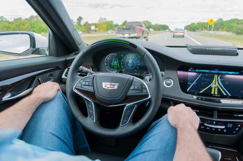 Man sitting in the driver’s seat of a self-driving vehicle with both of his hands on his knees 