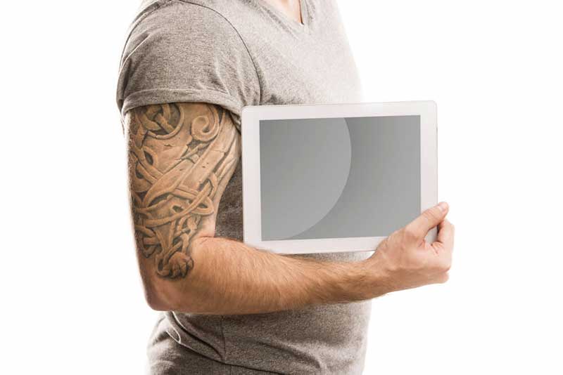 man in a grey shirt with a tattoo holding a tablet