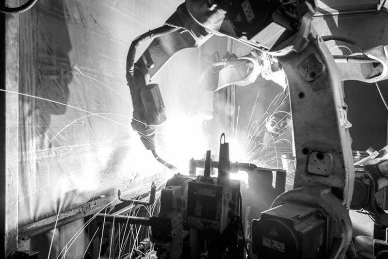 black-and-white photo of robotic arms welding