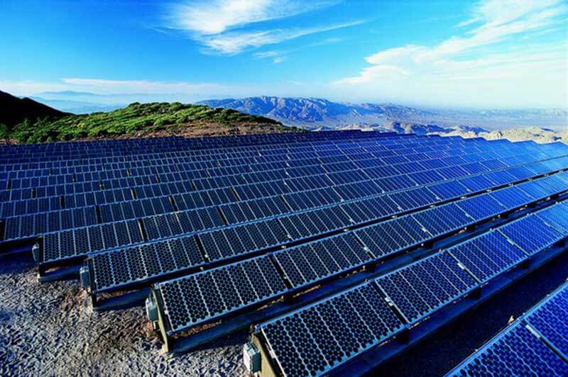 A solar farm with a green and mountainous landscape in the background