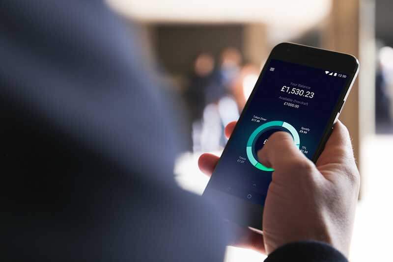 A person holding a smartphone showing financial data on its display