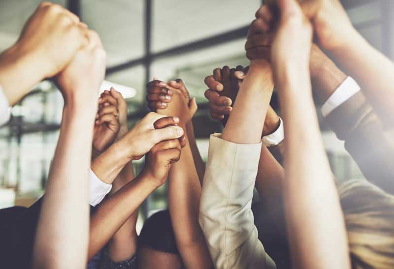 Young men and women holding hands high up