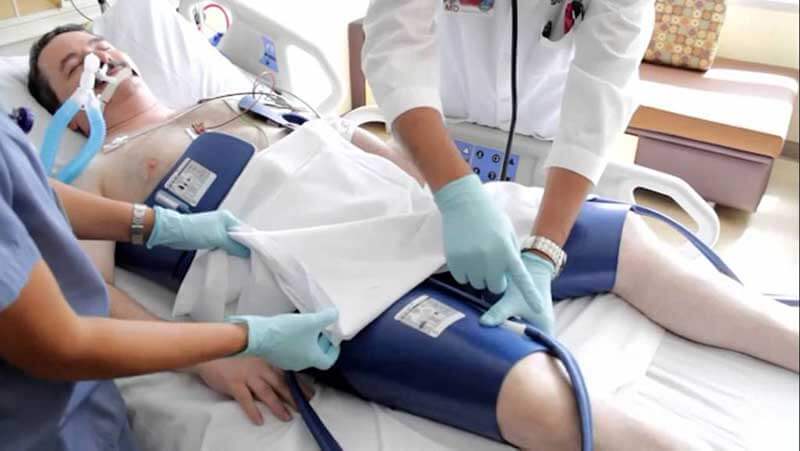  Two medical workers conducting therapeutic hypothermia on a patient lying in bed