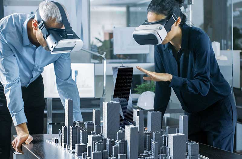 Two people with VR headsets looking at model of buildings