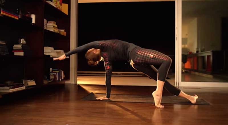 A woman exercising on a brown mat and wearing high-tech workout clothes