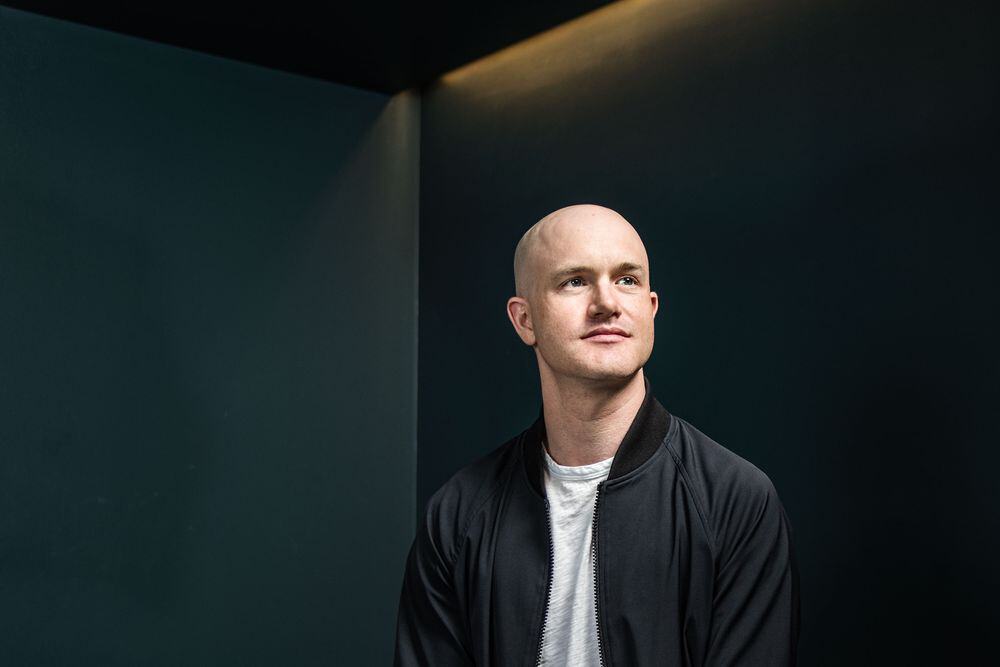 Een foto van Brian Armstrong, de CEO van Coinbase, met een wit T-shirt en een zwart jasje.