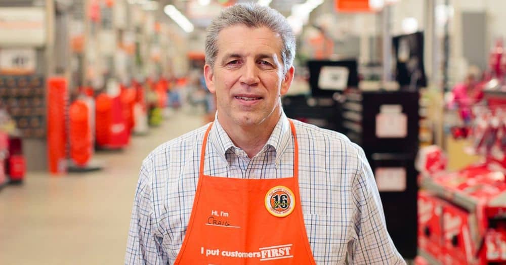 Een foto van Craig Menear, de CEO van The Home Depot, met een oranje schort met de tekst “'I put customers first”